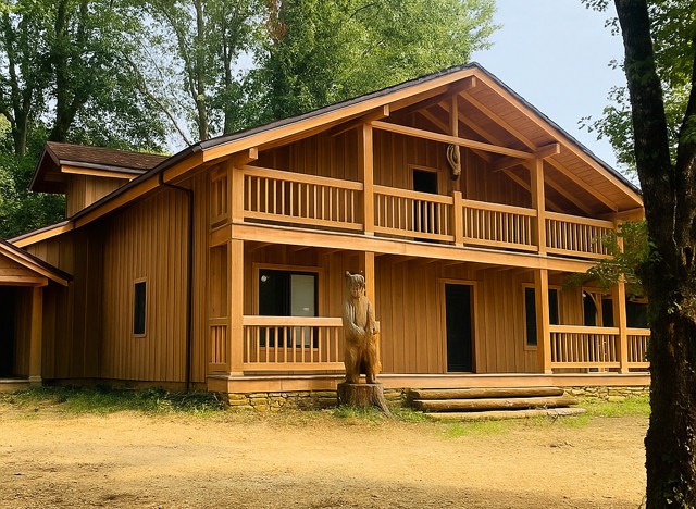 une grande maison en bois avec une sculpture en bois d'un ours devant l'entrée
